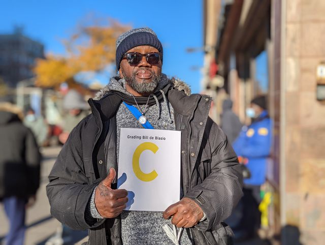 Ricky Singleton of Harlem holds up a sign grading de Blasio: a "C".